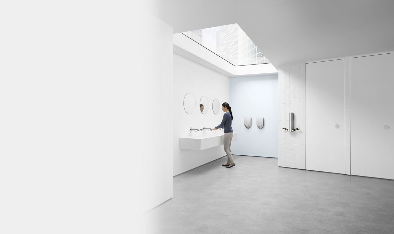 Mulher a utilizar o secador de mãos Dyson Wash+Dry numa casa de banho pública. 